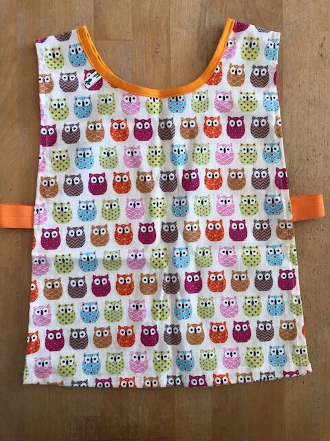 Tablier maternelle en coton avec élastiques sur les côtés, facile à enfiler et idéal pour les activités créatives des enfants.
